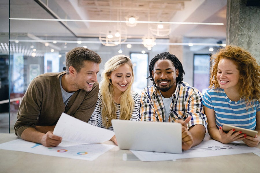 Group of coworkers looking at a laptop in the office